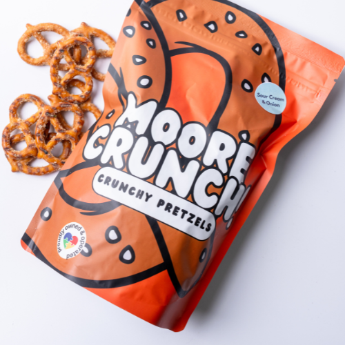 A package of Moore Crunch pretzels with the flavor Sour Cream & Onion. The package is orange with text and pretzel images on it, and a few pretzels are displayed outside of the package.